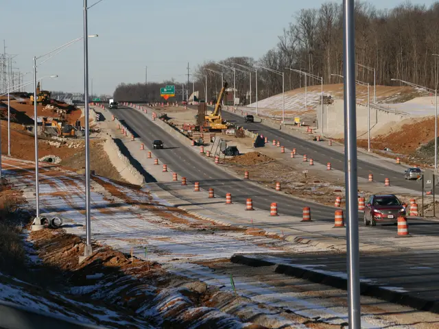 The image shows a highway with construction equipment on the side of it, including vehicles on the...