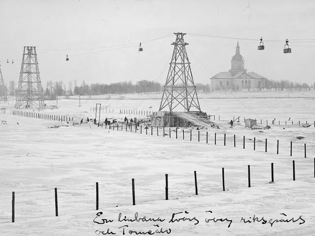 The image shows a black and white photo of a ski lift in the middle of a snowy field, surrounded by...