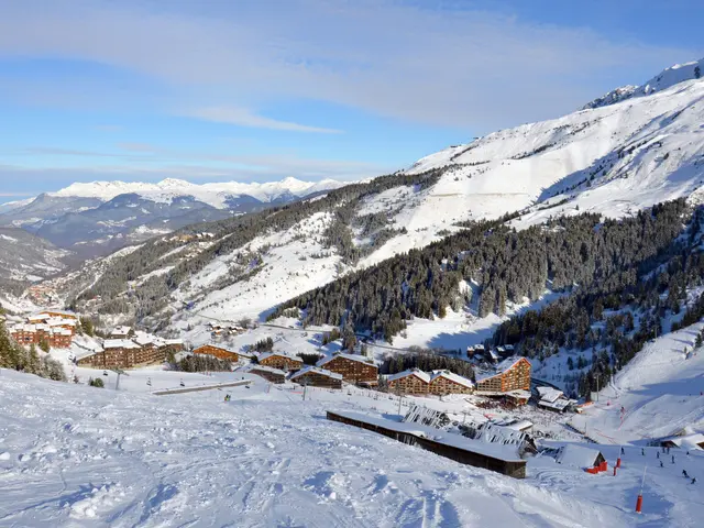 The image shows a picturesque view of a ski resort in the French Alps, with snow-covered mountains...