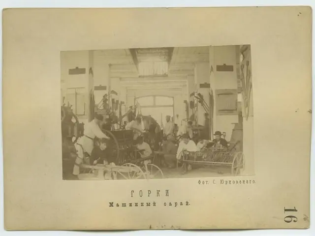 The image shows an old black and white photo of a group of people working in a factory, with a...