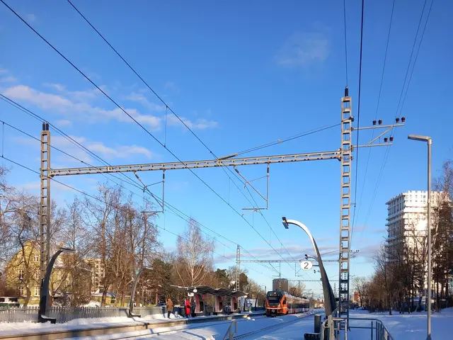 The image shows a ski lift going down a snowy hill with power lines in the background. There are...