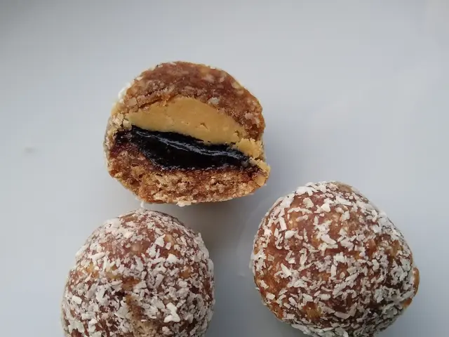 The image shows three chocolate and peanut butter balls on a white plate with a bite taken out of...
