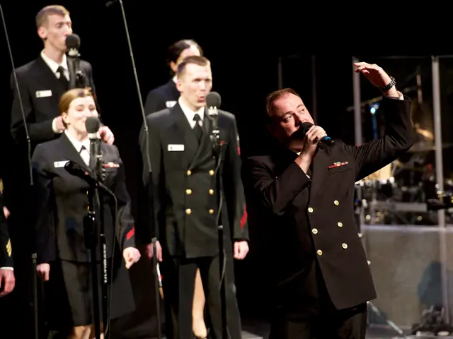 The image shows a group of men in military uniforms standing on a stage, singing into microphones...