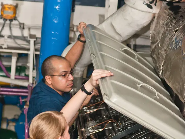 The image shows two people working on an engine in a factory. The man and woman are standing in...