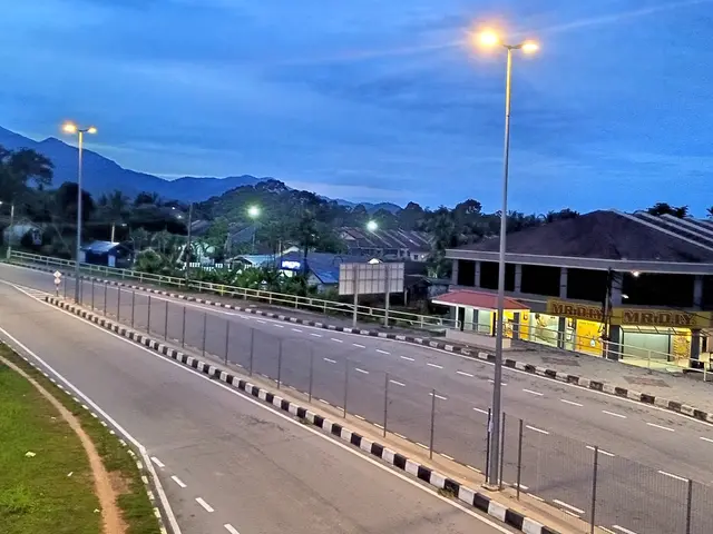 The image shows a highway at night with street lights illuminating the road, a fence running along...