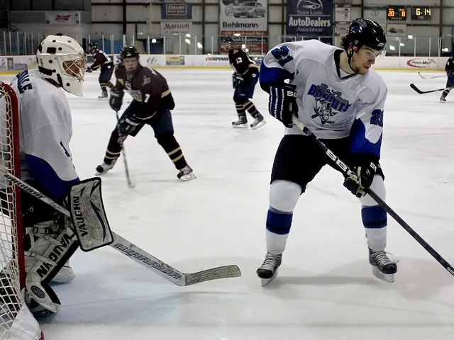 The image shows a group of young men playing a game of ice hockey on an ice rink. They are all...