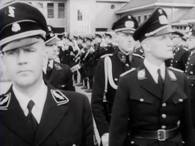 The image shows a group of men in military uniforms standing next to each other, wearing caps and...