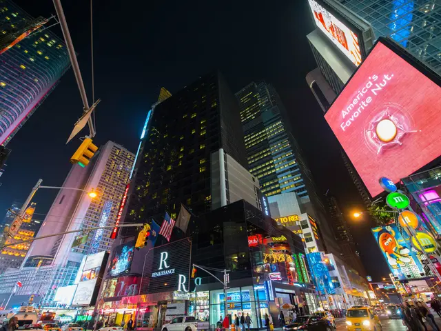 The image shows Times Square in New York City at night, with vehicles on the road, people walking...