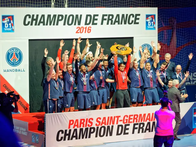 The image shows a group of men standing on top of a stage, proudly holding up a trophy. On the left...