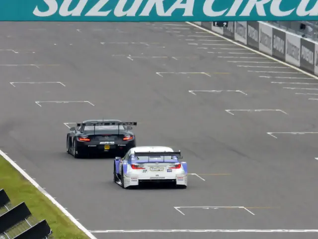 The image shows two sports cars racing on a race track with a sign that reads "Suzuka Circuit" in...