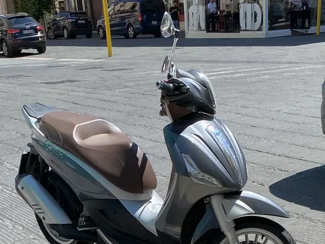 The image shows a motor scooter parked on the side of a street, with a helmet on the scooter. In...