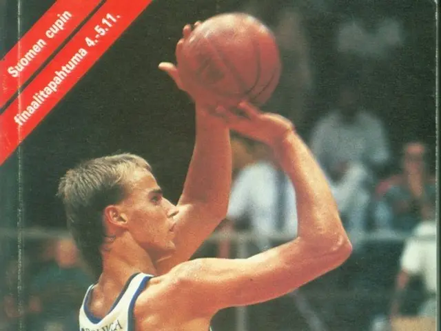 The image shows a man shooting a basketball in front of a crowd. He is wearing a basketball uniform...