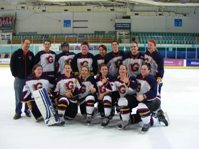 The image shows a group of women's hockey players posing for a photo on the ice. They are all...