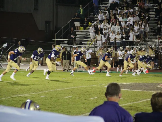 The image shows a football game being played on a grassy field with people wearing sports dress and...