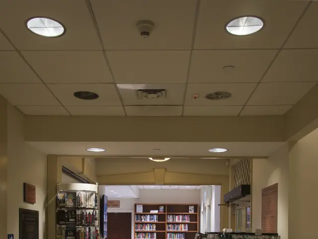 The image shows a library with bookshelves filled with books on the racks, a tiled floor, chairs, a...