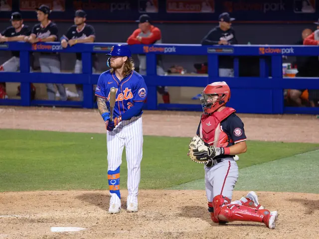 The image shows a baseball player standing on top of a field next to a catcher. The player is...