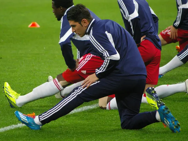 The image shows a group of men playing soccer on a grassy field. They are wearing sports attire and...