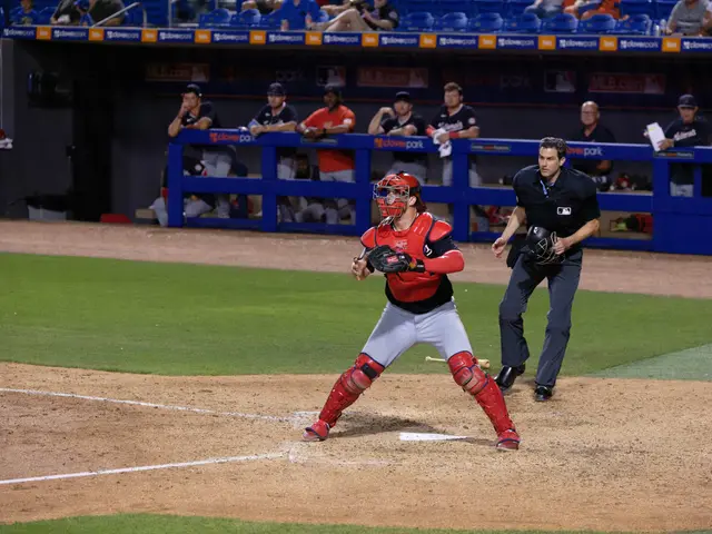 The image shows a baseball player wearing a helmet and gloves, swinging a bat on top of a field. In...