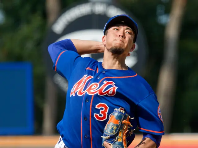 The image shows a baseball player wearing a blue t-shirt, white pants, a blue cap, and blue shoes,...