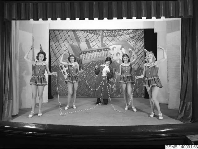 The image shows a group of five women standing on top of a stage, smiling and holding ropes in...