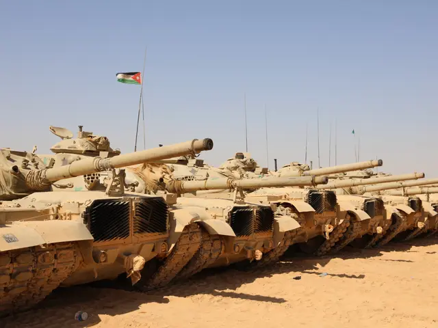 The image shows a row of military tanks lined up in the desert, with a Jordanian flag flying atop...