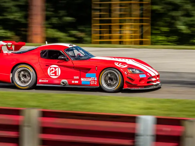 The image shows a red and white Dodge Viper GTS-R on a race track, surrounded by grass and a fence...