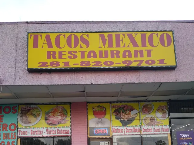 The image shows a taco mexico restaurant on the corner of a street, with a road in the foreground...