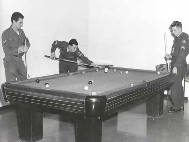 The image shows three men playing pool in a room. They are standing around a pool table, each...