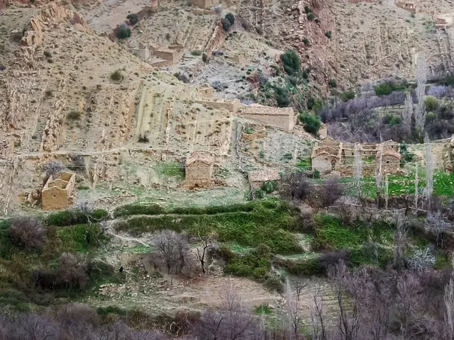 The image shows a small village nestled in the middle of a mountain, surrounded by trees, plants,...