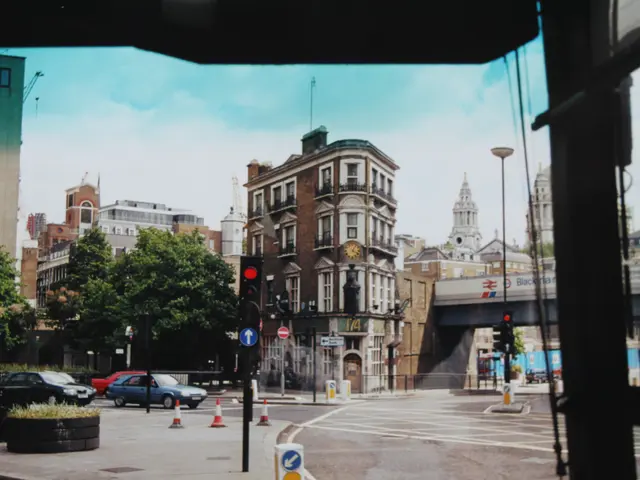 The image shows a view of a city street from a bus window. We can see vehicles on the road, traffic...