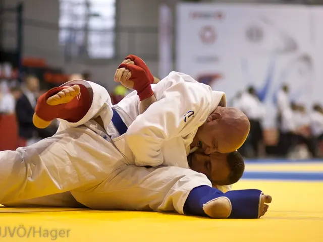 The image shows two judo fighters in the center of the frame, engaged in a judo match. In the...