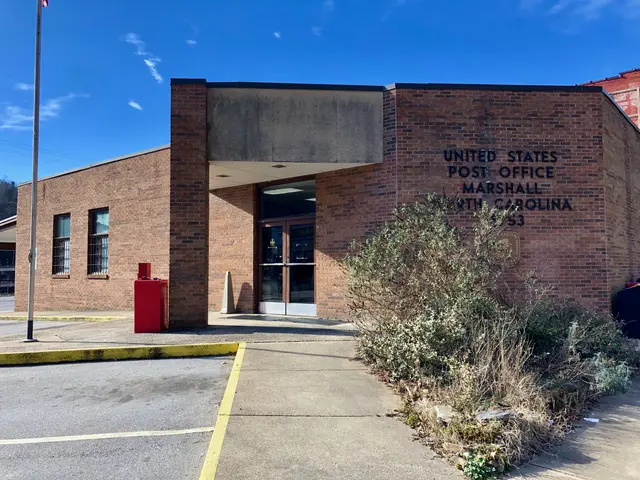 The image shows the United States Post Office in Marshall, North Carolina. It is a brick building...