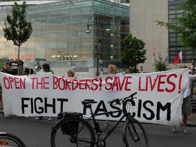 The image shows a group of people standing on the road, holding a banner that reads "Open the...