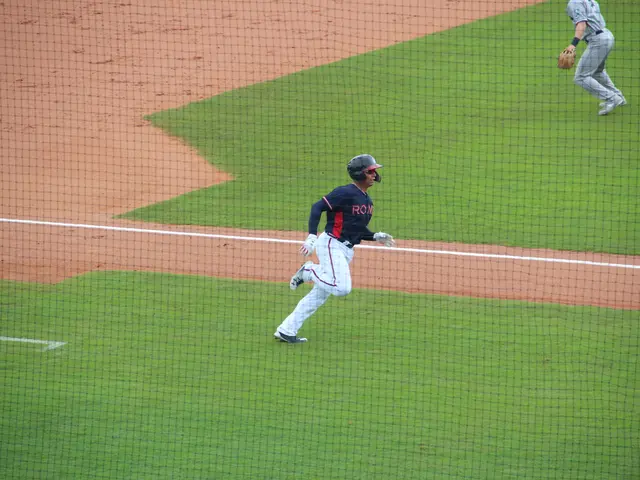 The image shows a baseball player wearing a helmet and gloves, running to first base during a game....