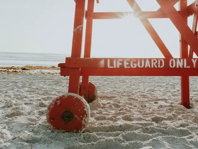 The image shows a red lifeguard stand on the beach with the words "Lifeguard Only" written on it....