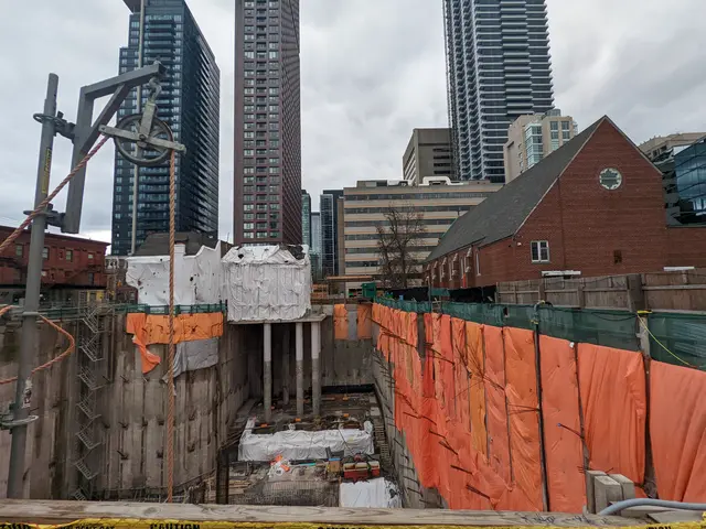 The image shows a construction site with a large building under construction in the background,...