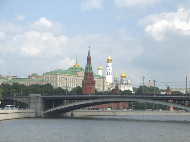 The image shows a bridge spanning a body of water, with vehicles driving on it, light poles lining...