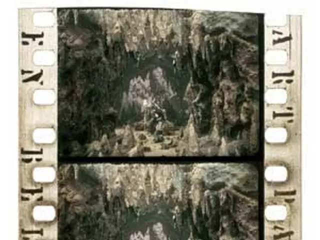 The image shows a film strip with a black and white photo of a group of people in a cave, with the...
