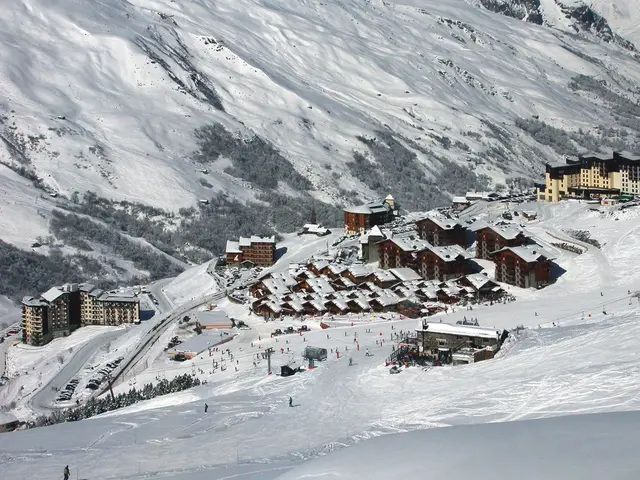 The image shows a picturesque view of a ski resort in the French Alps, with snow-covered mountains...
