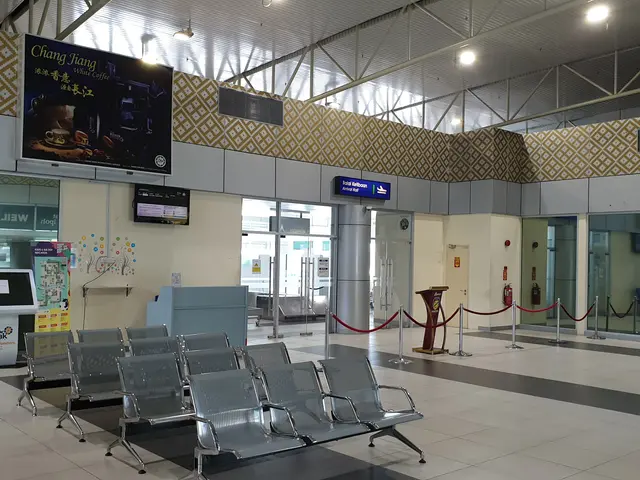 The image shows an empty waiting area in an airport with chairs on the floor, barrier poles with...