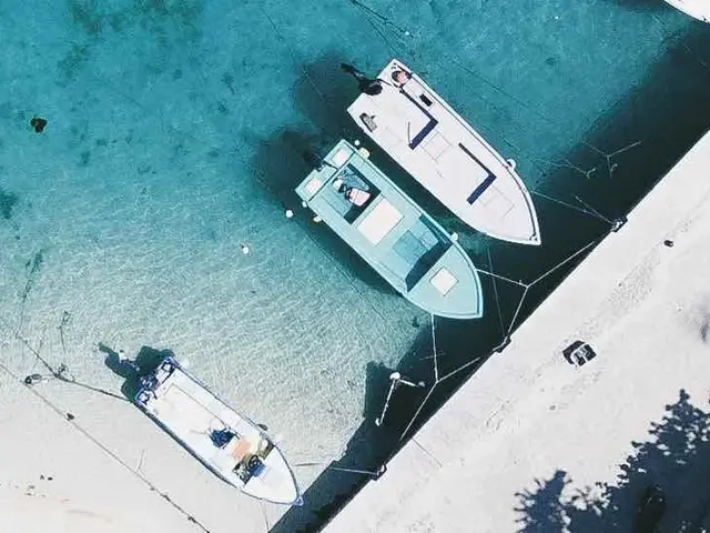 The image shows an aerial view of a beach with boats docked in the water, surrounded by lush green...