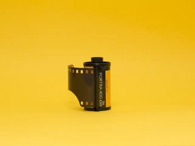 The image shows a roll of 35mm film on a bright yellow background, creating a vivid contrast...
