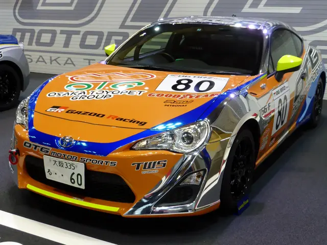 The image shows a Toyota GT86 race car on display at the Tokyo Motor Show. The car is painted in an...