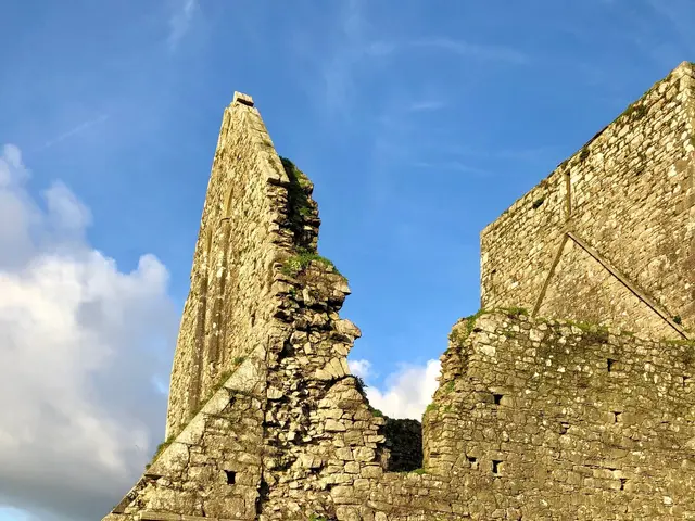 The image shows the ruins of an old stone abbey in Ireland, surrounded by lush green grass and...