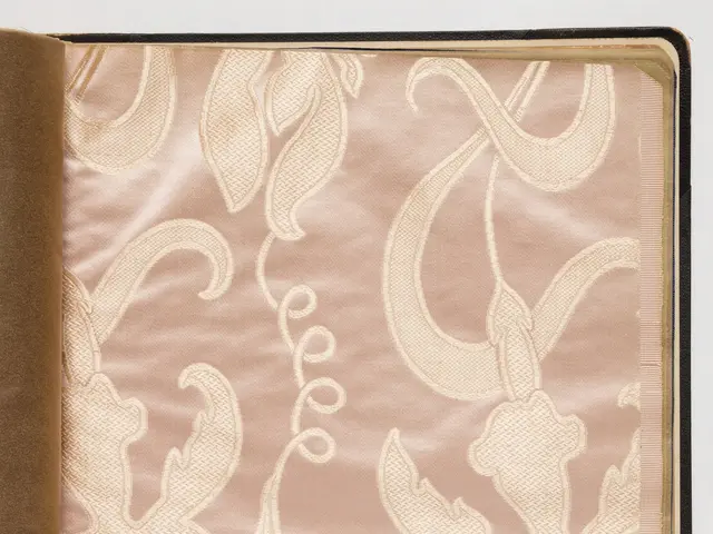 The image shows an open book with a pink and gold design on it, set against a white background. The...