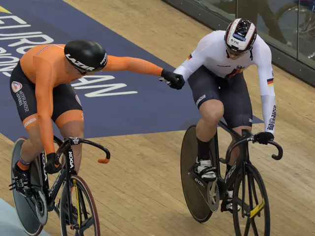 The image shows two men wearing helmets and riding bicycles on a track, with a glass wall in the...