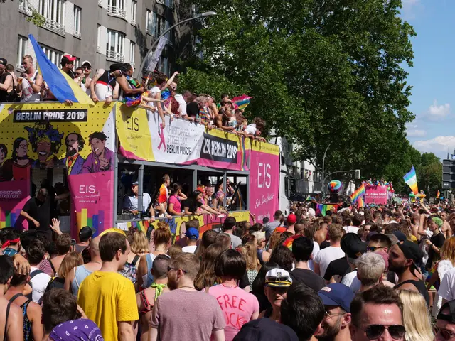 The image shows a large crowd of people walking down a street in Berlin Pride 2019. Many of them...