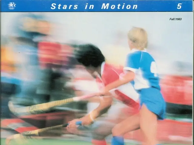 The image shows two women playing field hockey on a field, each holding a hockey stick and a ball...