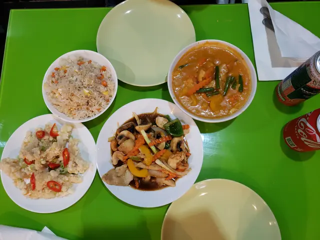 The image shows a green table topped with plates of food and drinks, including a can, tissue...