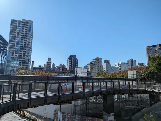 The image shows a bridge over a river with tall buildings in the background. The bridge has...